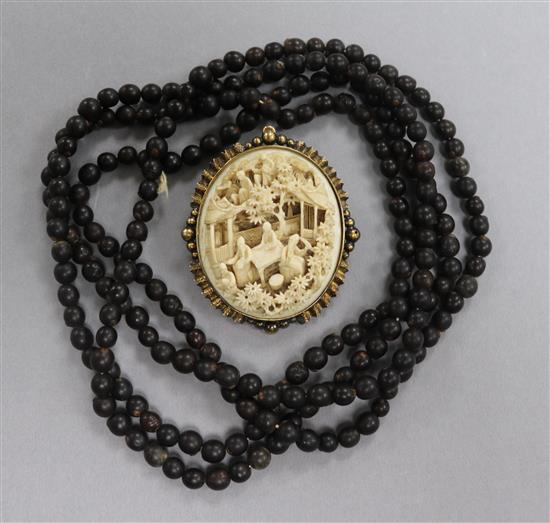 A Victorian gilt white metal and Chinese ivory brooch and a Buddhist seed rosary necklace.
